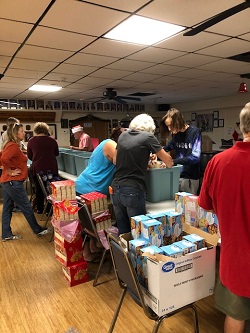 Volunteers working hard preparing food baskets.  This effort feeds typically 80 local families with food and essentials during the holiday season. 