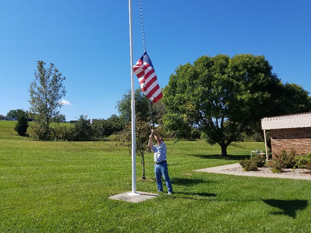 Craig Robinson lowering the worn flag at Valley manor to replace it with a new one
