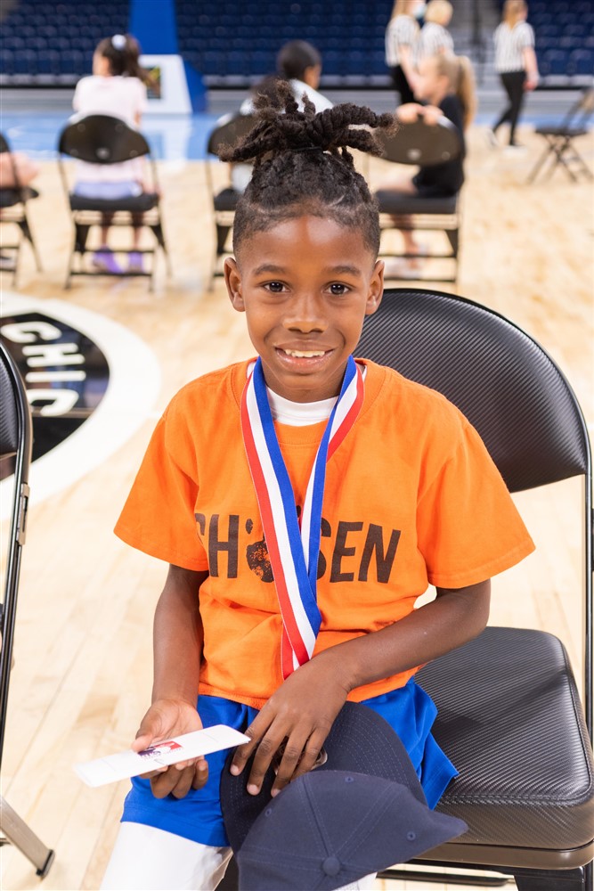 Croix smiles while wearing his gold hoop shoot medal and holding his national champion hat