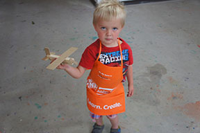 picture of child holding homemade wooden plane